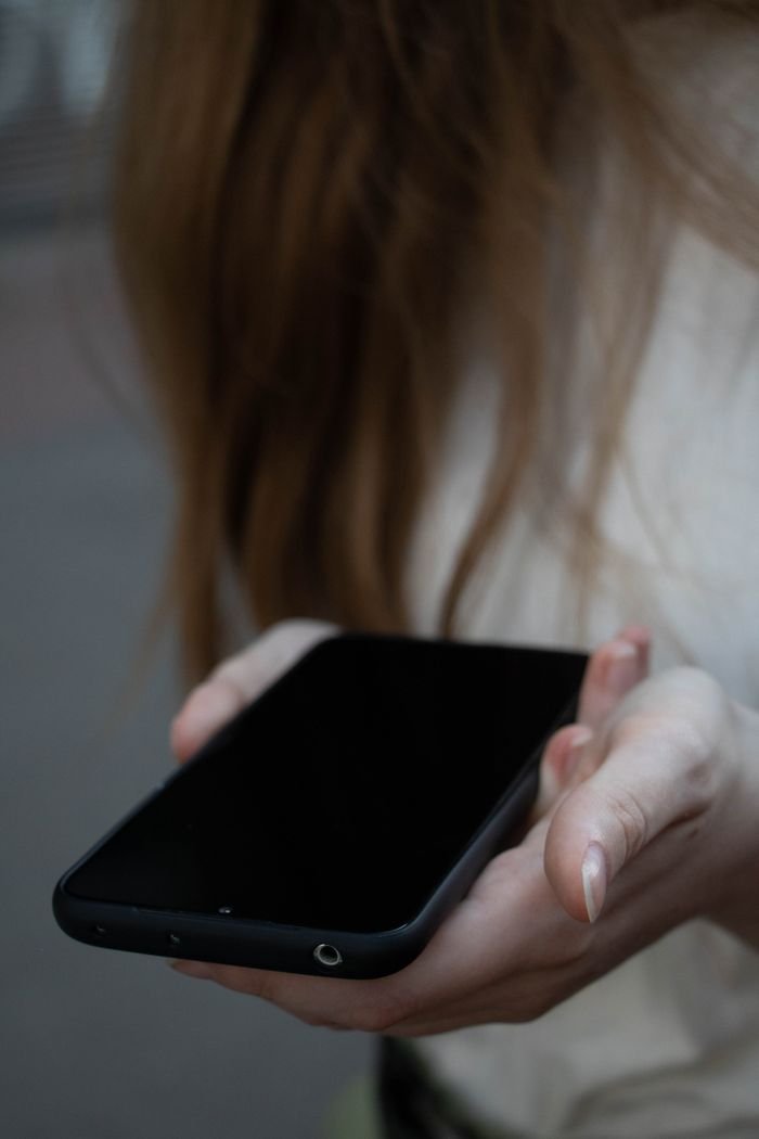 Close-up of a person holding a smartphone outdoors, showing screen and hands in soft focus.