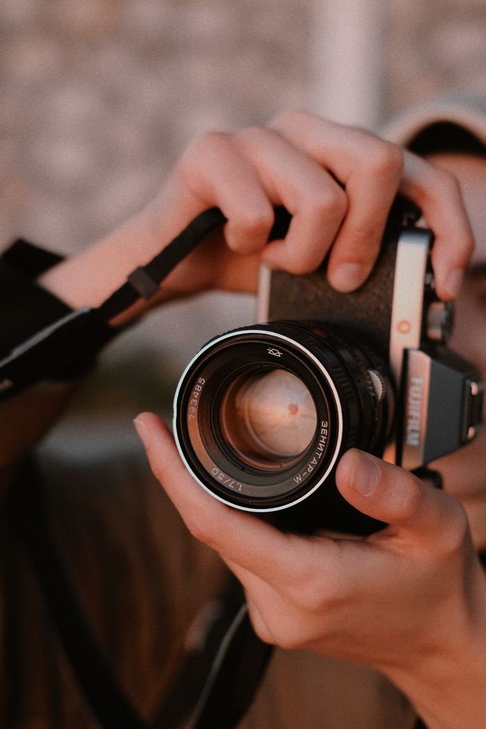 Close-up of hands holding a vintage camera, highlighting the classic lens.